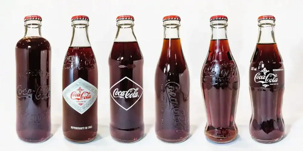 Six vintage Coca-Cola glass bottles lined up on a white background