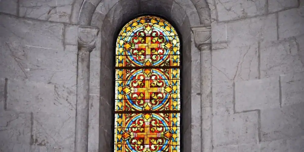 Arched colorful stained glass window in a stone wall