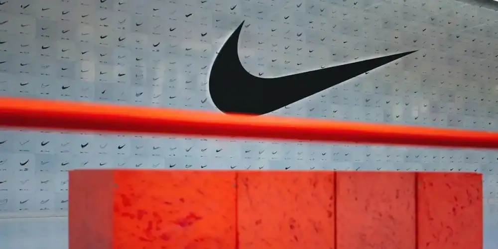 Nike store interior with a large swoosh logo, red light bar, and orange-red display pedestal