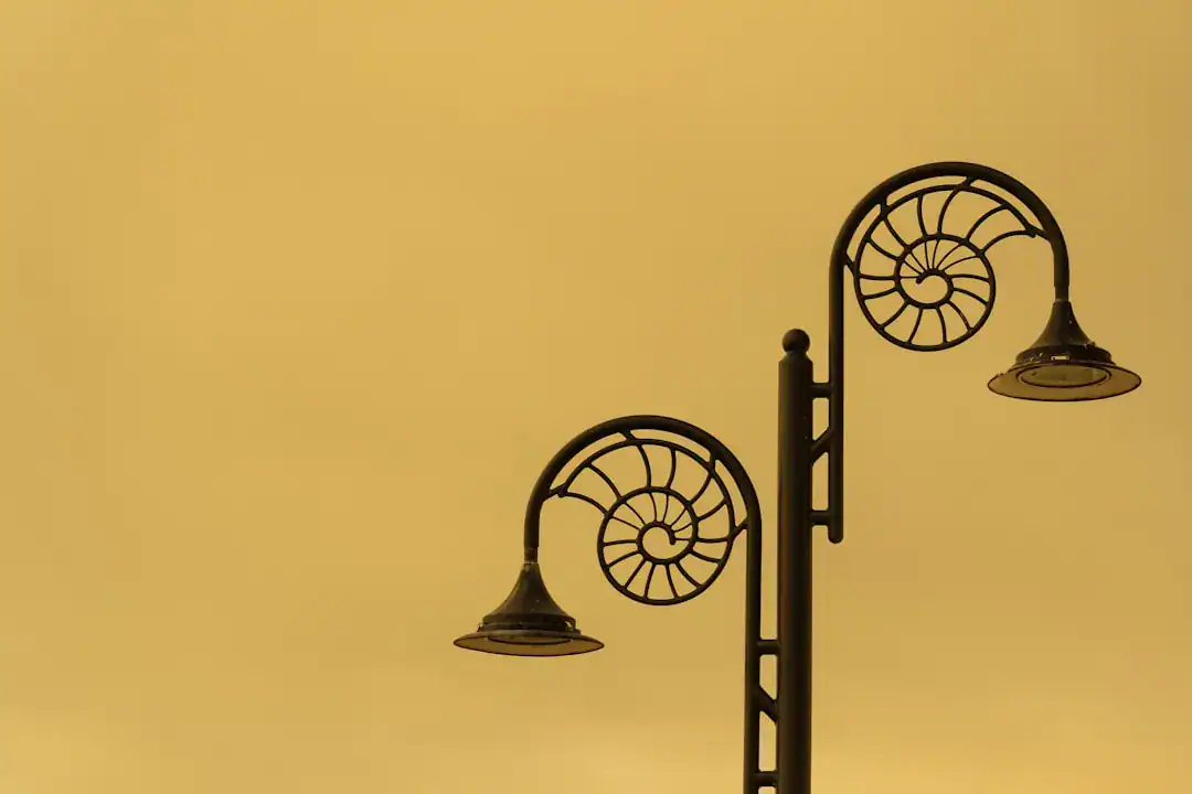Silhouetted ornate street lamps against a yellow sunset sky