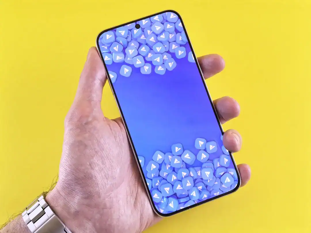 Hand holding smartphone with blue gradient screen full of play icons on yellow background