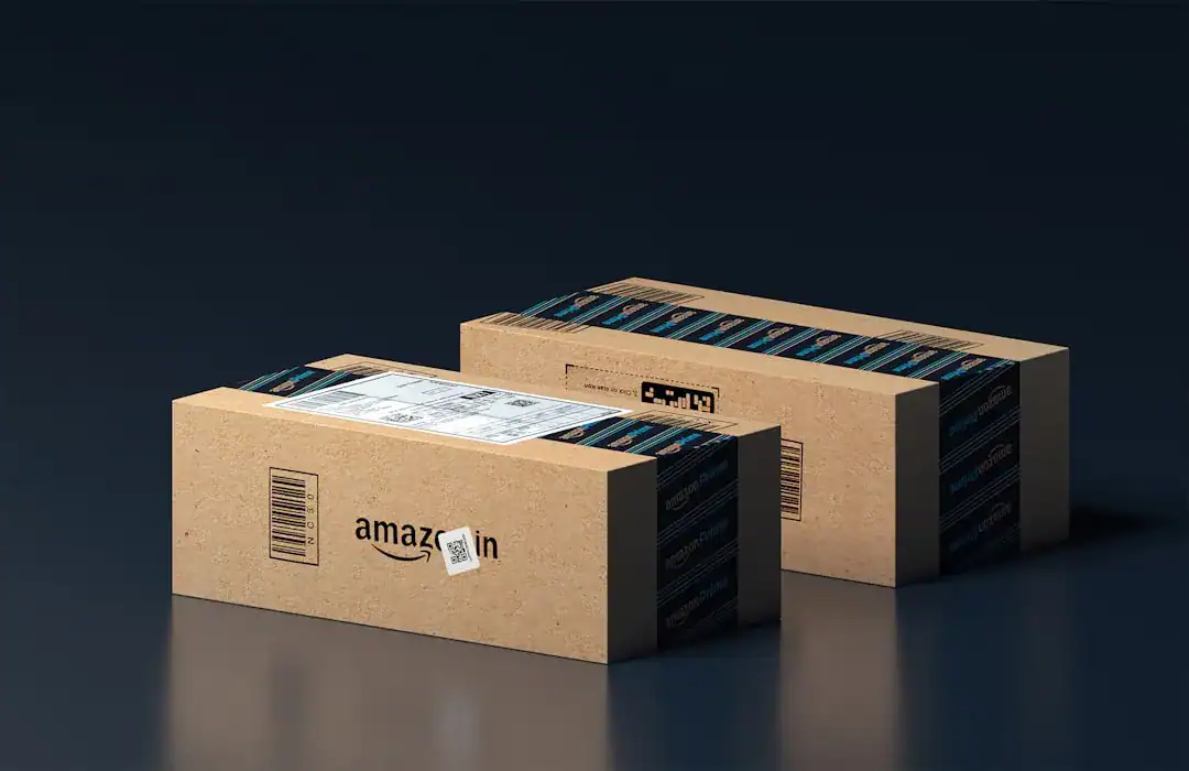 Three brown Amazon shipping boxes sealed with blue tape on a dark surface