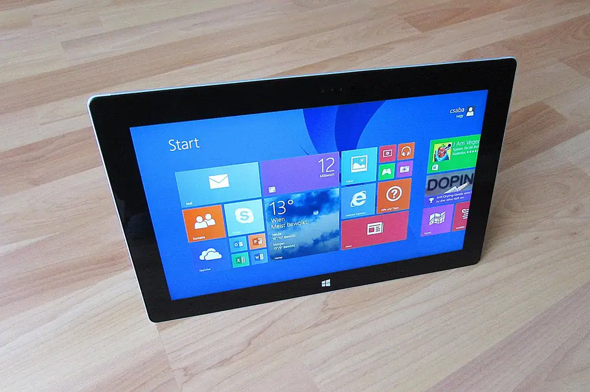 Windows tablet on wooden floor showing Start screen