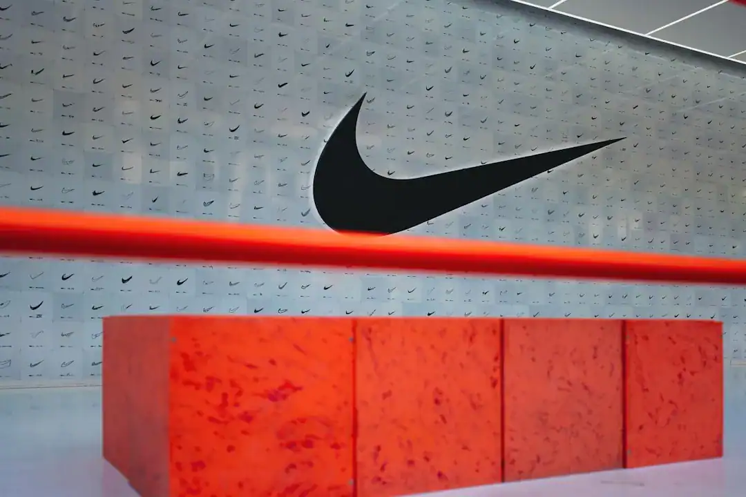 Nike store interior with a large swoosh logo, red light bar, and orange-red display pedestal
