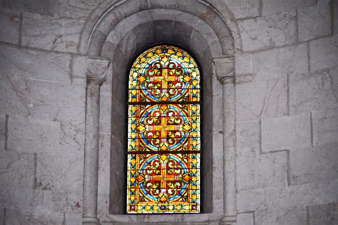 Arched colorful stained glass window in a stone wall