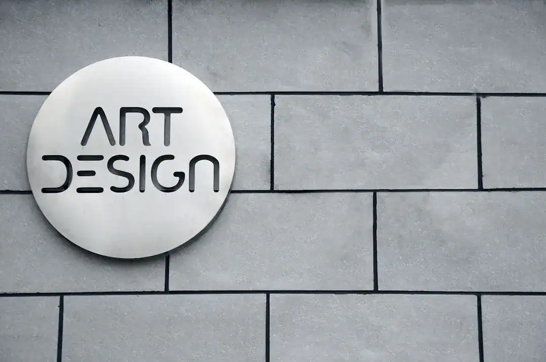 Round white sign with ART DESIGN text on a gray tiled wall