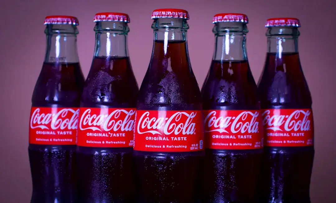 Five classic Coca-Cola glass bottles with red labels and caps lined up