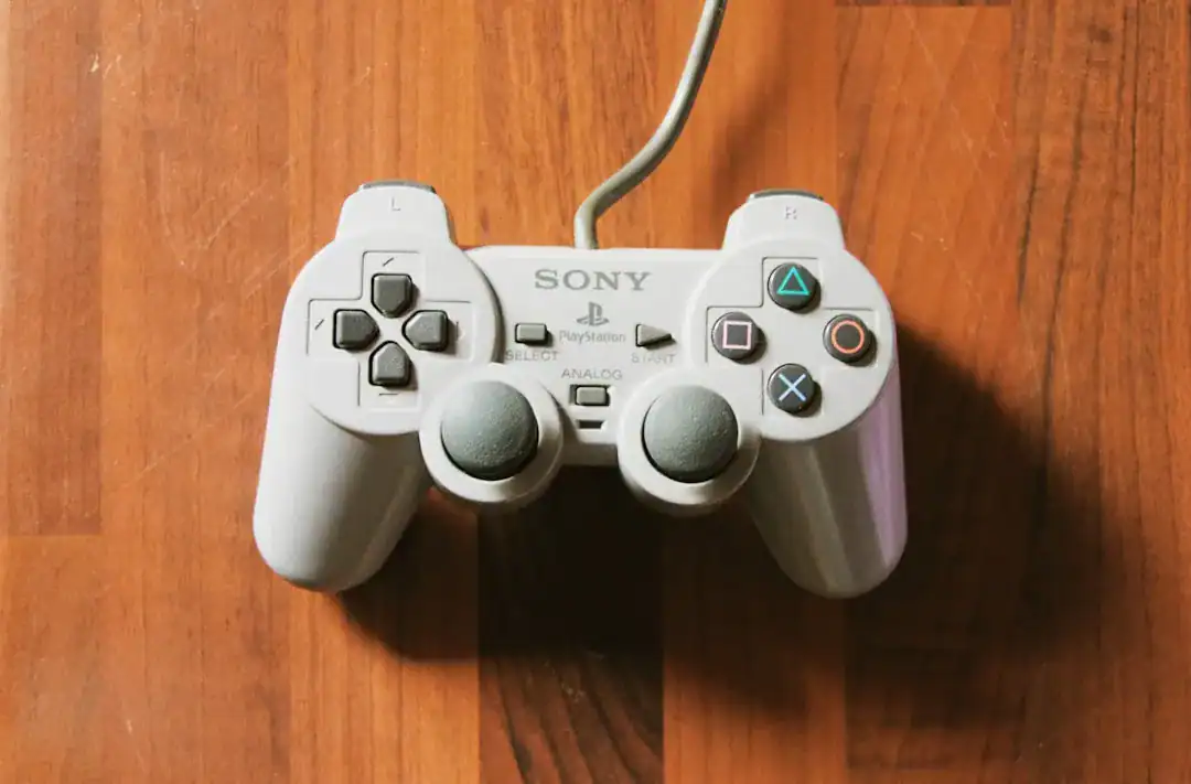 Classic gray Sony PlayStation DualShock controller on a wooden floor with a visible cord
