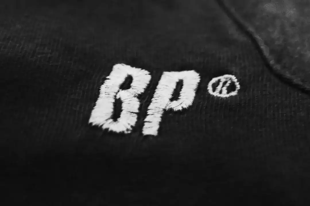 Close-up of white BP embroidery on black fabric