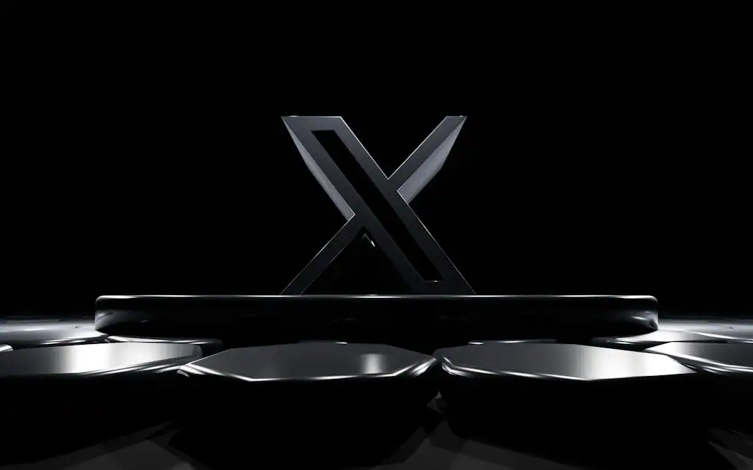 Metallic X logo with a bar and circular metal discs on a dark glossy surface