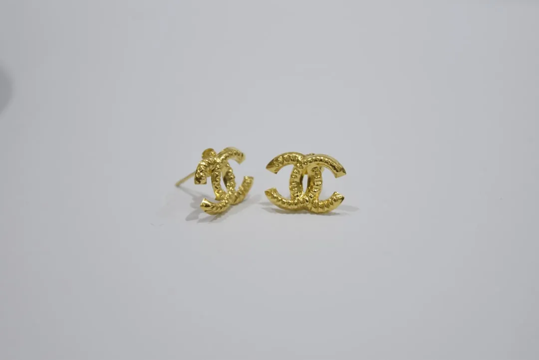 Gold-tone Chanel logo earrings on a light background