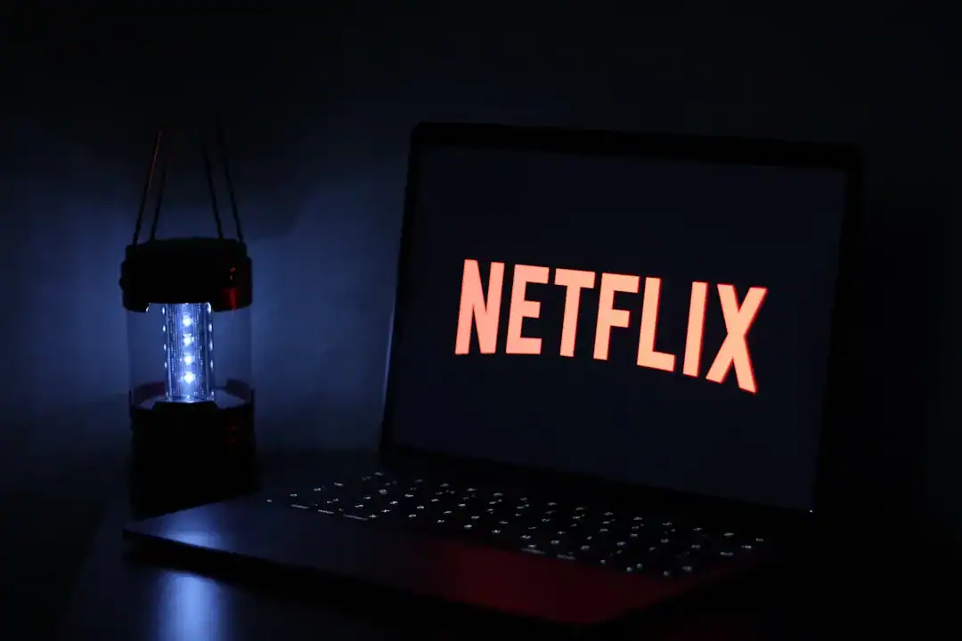 Laptop displaying Netflix logo in a dark room beside a glowing blue lantern