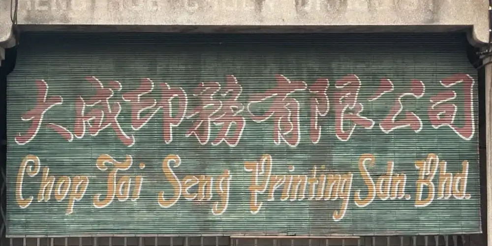 Shuttered storefront sign with Chinese characters and 'Chop Tai Seng Printing Sdn. Bhd.'