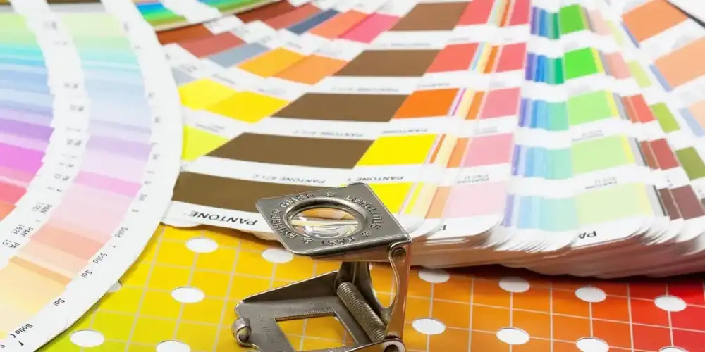 Metal clamp resting on colorful color swatch decks over a yellow grid