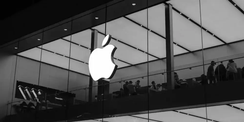 Large Apple logo on glass storefront with shoppers on a mezzanine.