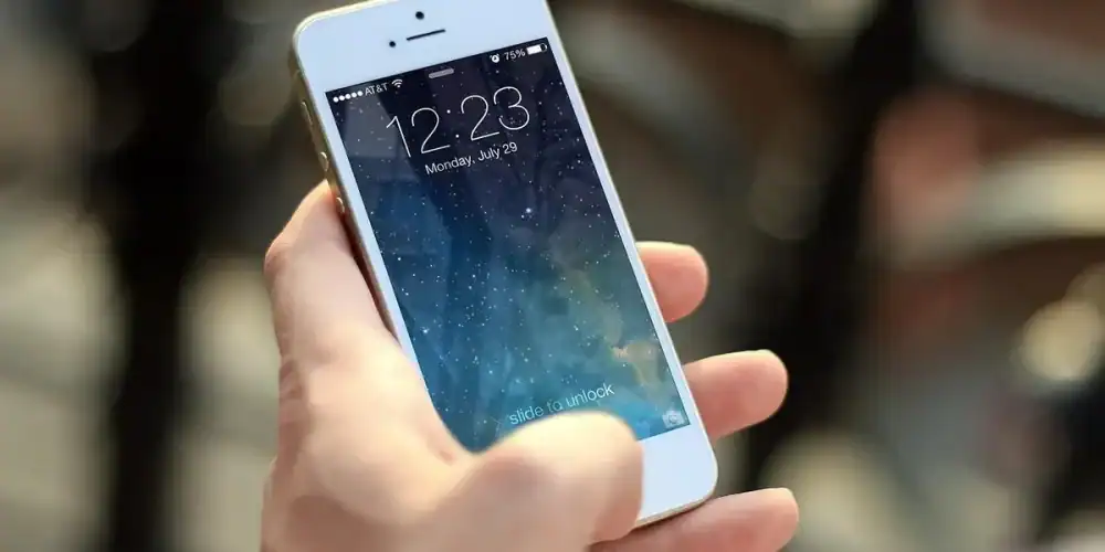 Hand holding a white iPhone showing a starry lock screen