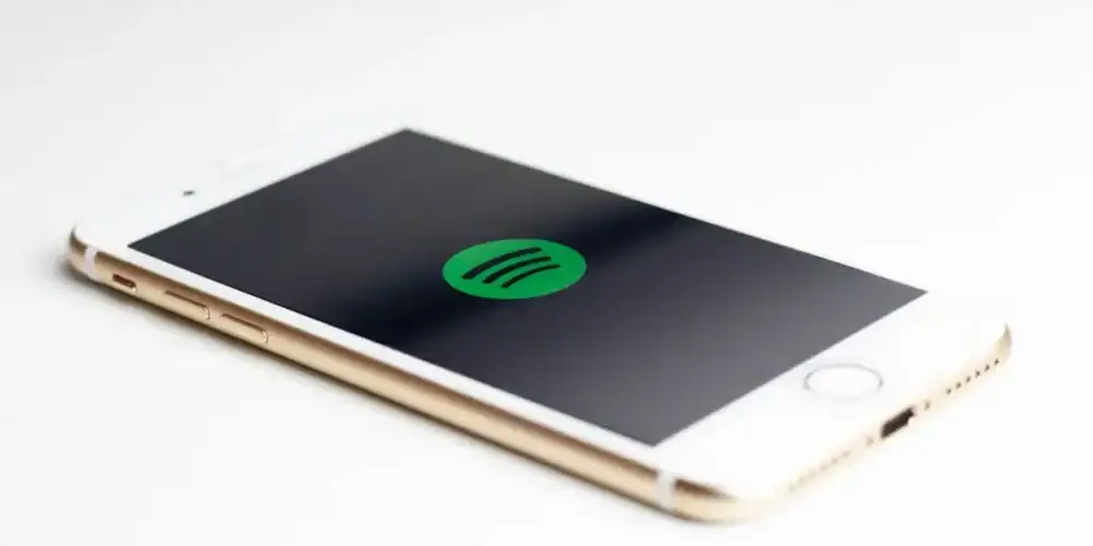 White and gold iPhone displaying the Spotify logo on screen