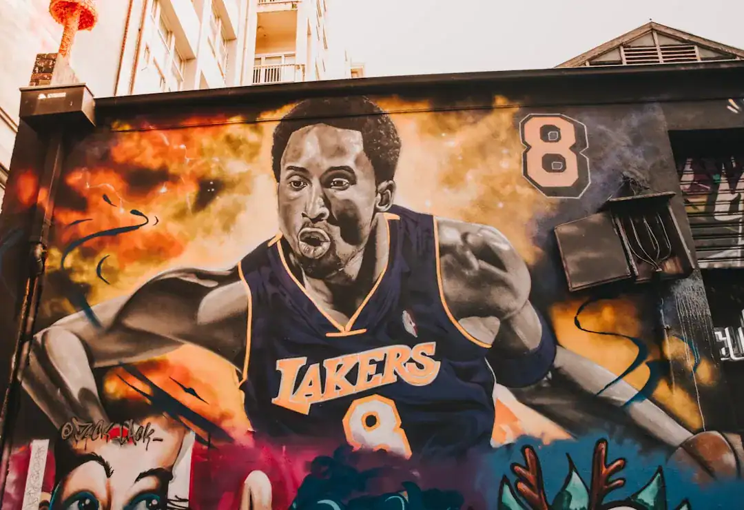 Vibrant street mural of a muscular basketball player in a Lakers jersey #8 against a fiery background