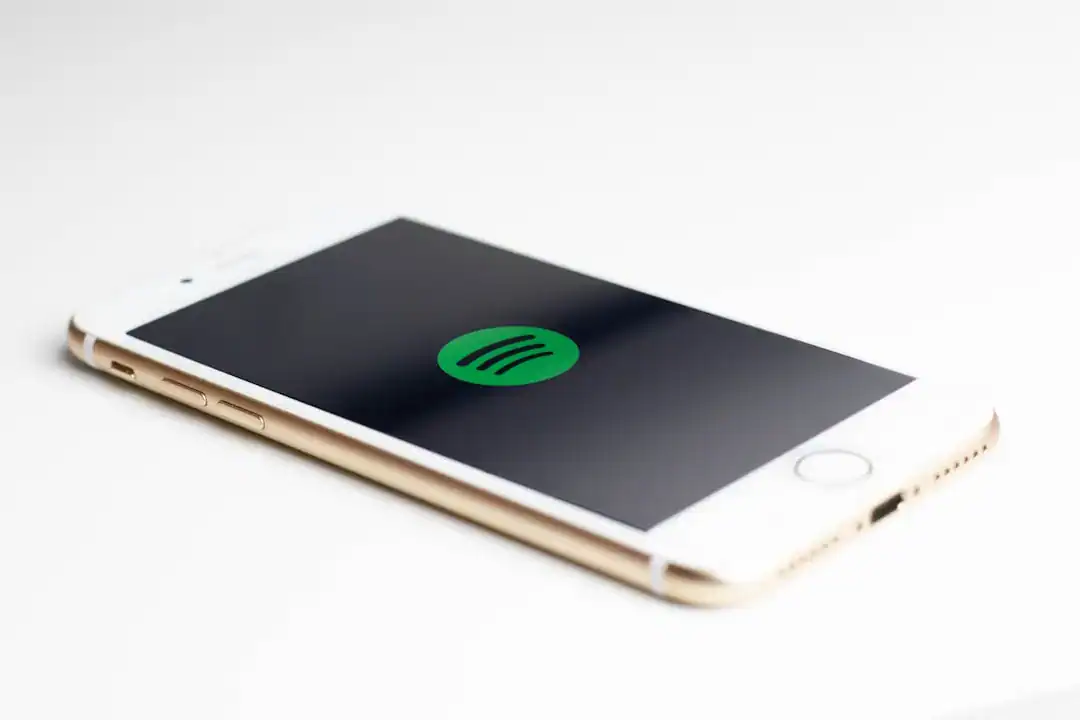 White and gold iPhone displaying the Spotify logo on screen