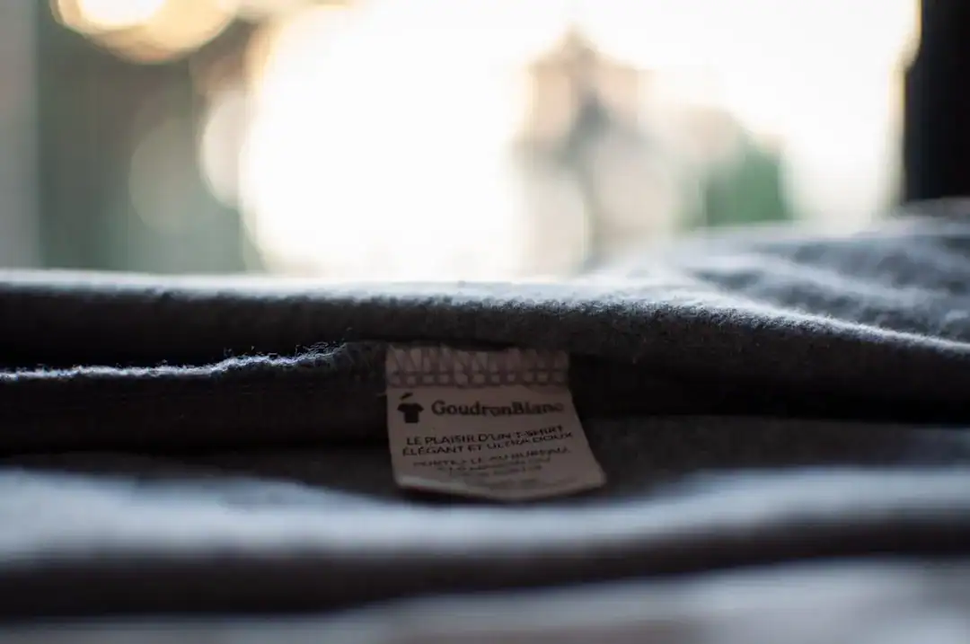 Close-up of a clothing tag on folded dark fabric with soft bokeh background