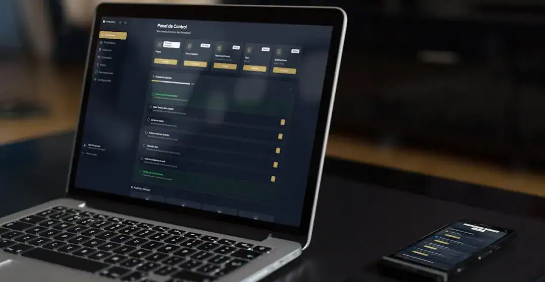 Dark Themed Control Panel Dashboard on Laptop with Mobile Device Laptop screen with dark control panel dashboard and a nearby mobile phone