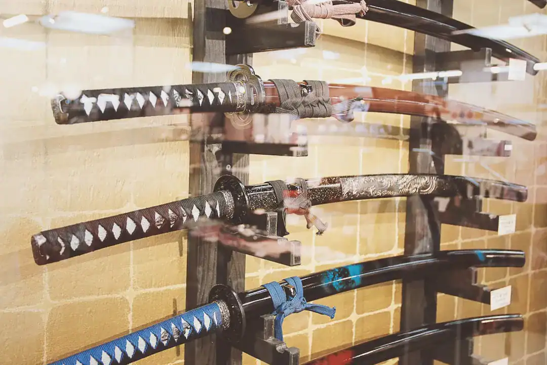 Several traditional katana swords with wrapped handles mounted on a wooden wall rack in a showroom.