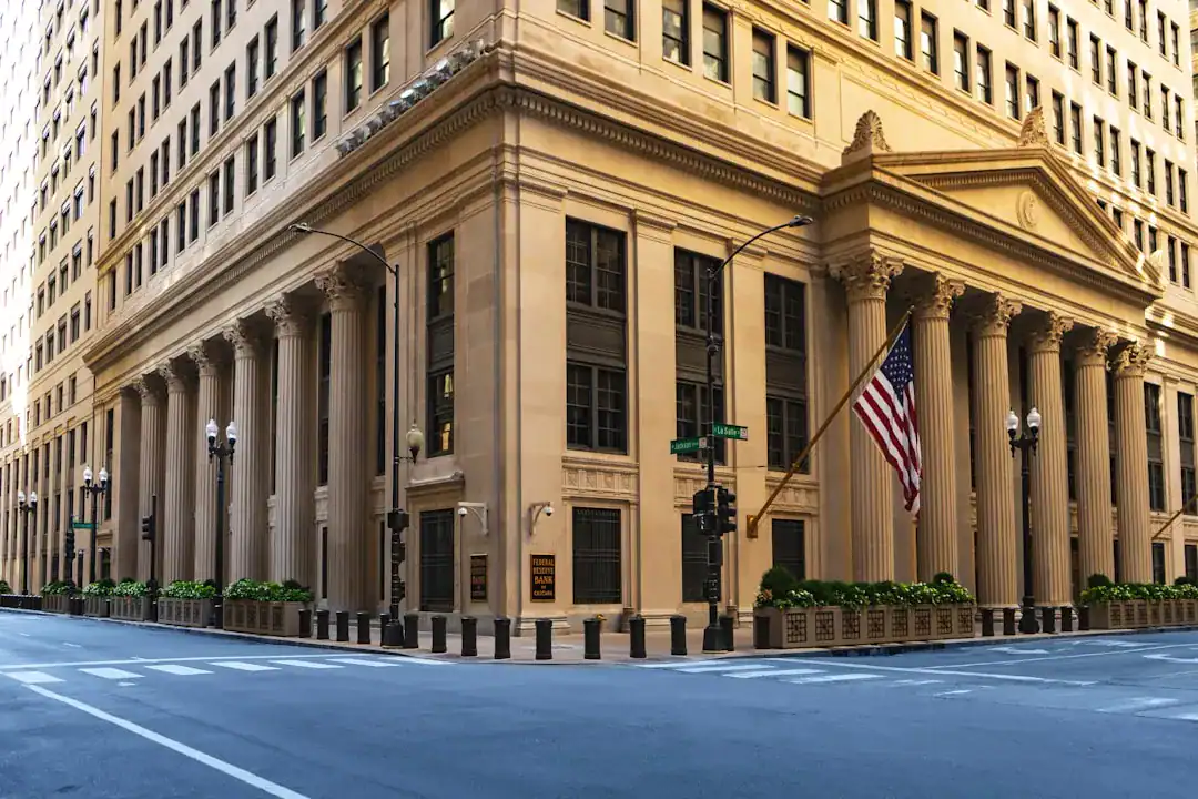 Beige neoclassical building with columns on a city street corner and an American flag