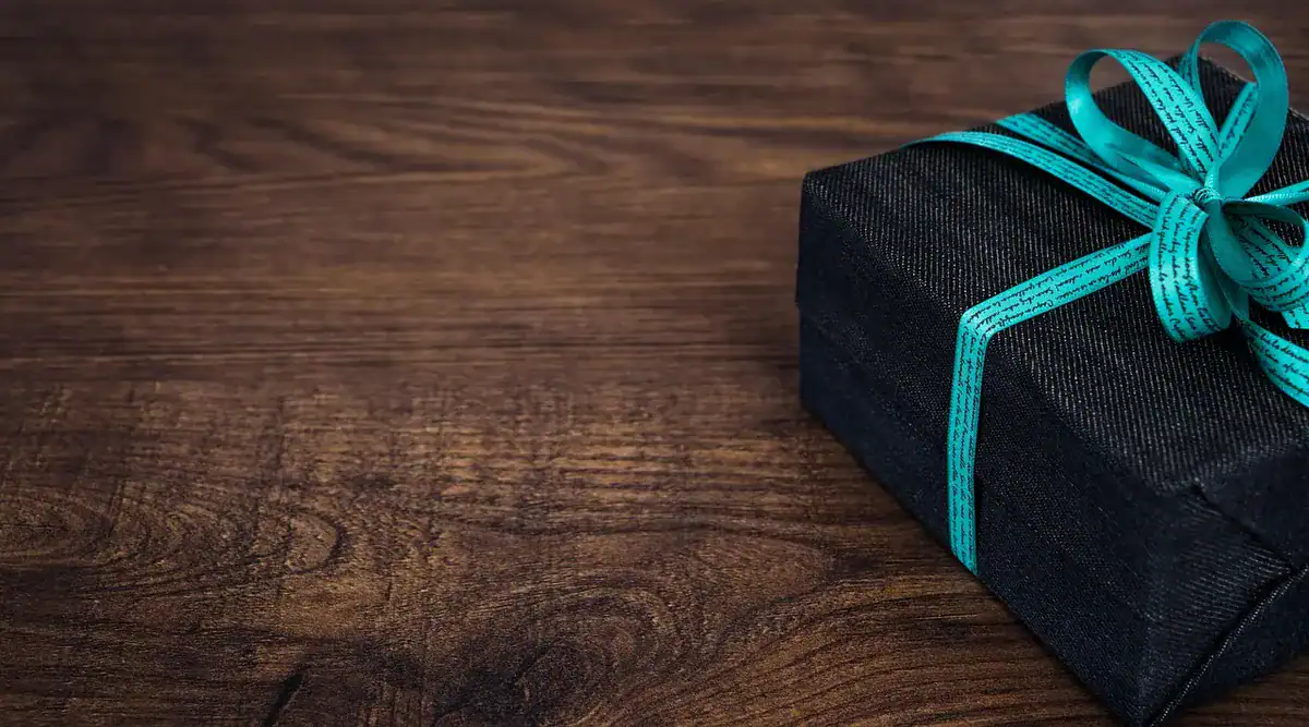 Black gift box with turquoise ribbon on wooden table