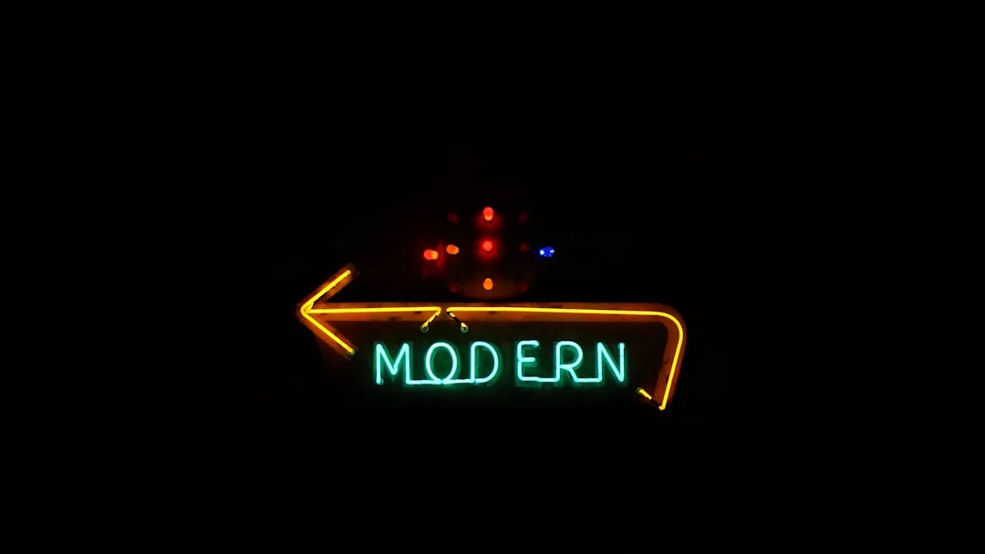 Neon sign reading MODERN with yellow arrow against a dark background