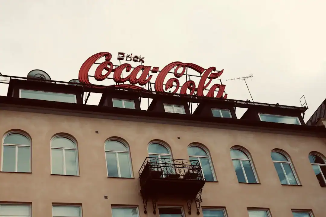 Coca-Cola sign on a beige building with arched windows and a small balcony
