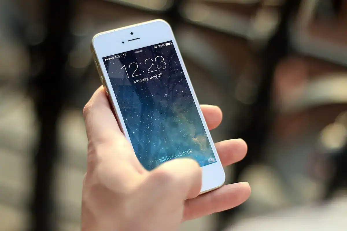 Hand holding a white iPhone showing a starry lock screen