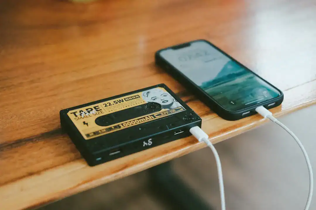 Vintage cassette and smartphone connected by a cable on a wooden table