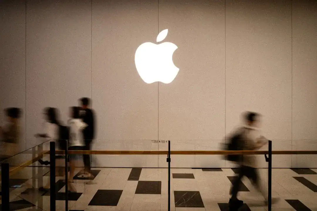 Illuminated Apple logo on wall as pedestrians move past