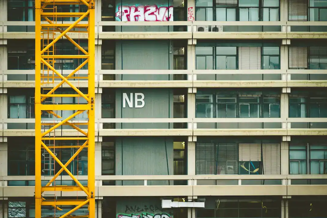 Yellow construction crane beside a multi-story concrete building under construction