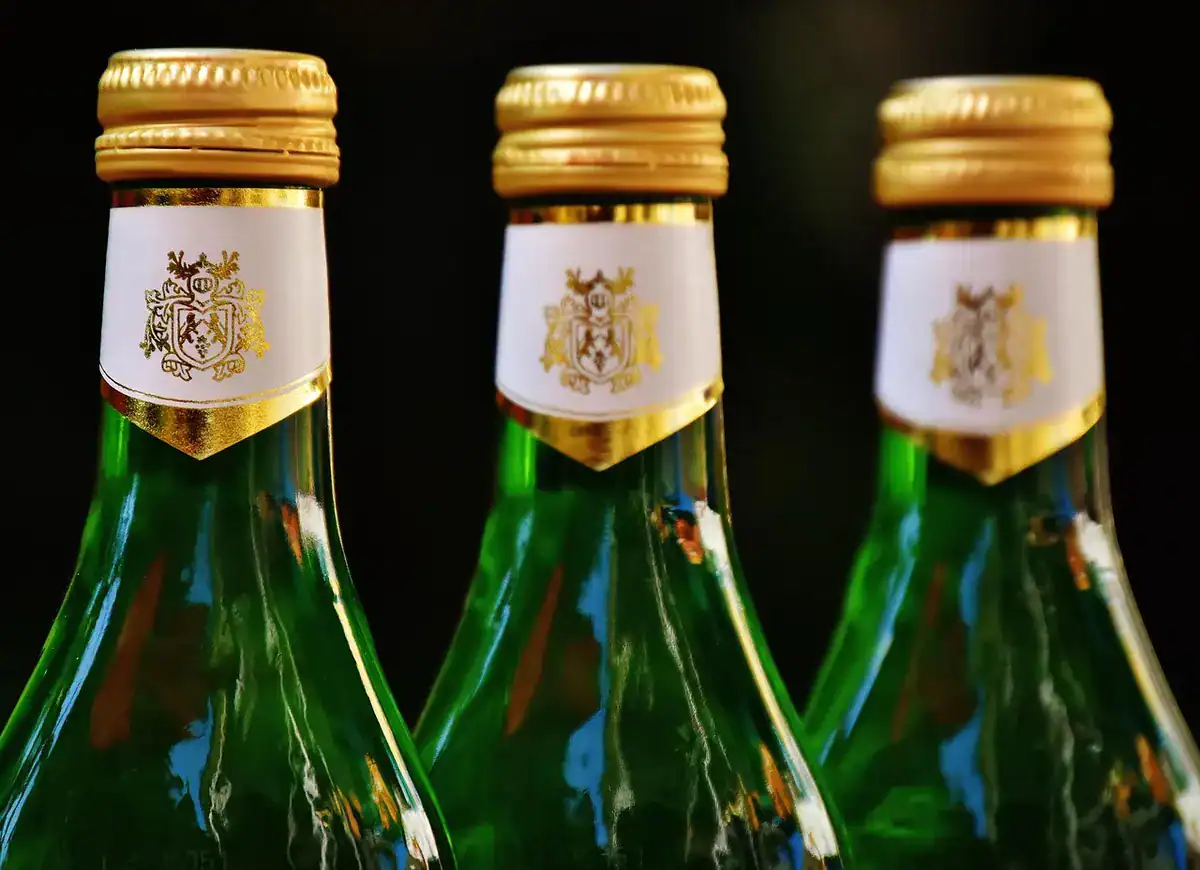 Three green champagne bottles with gold caps and crest labels