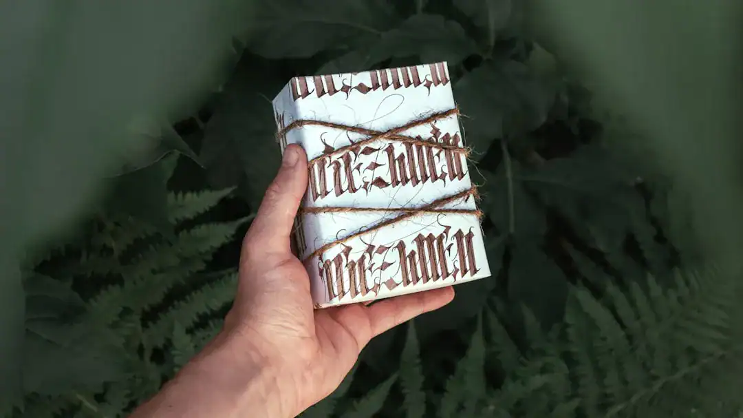 Person's hand holding three white-wrapped handmade soap bars outdoors