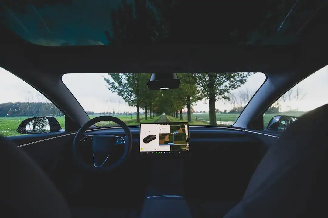 Sleek car interior with center touchscreen navigation and a tree-lined road visible through the windshield.