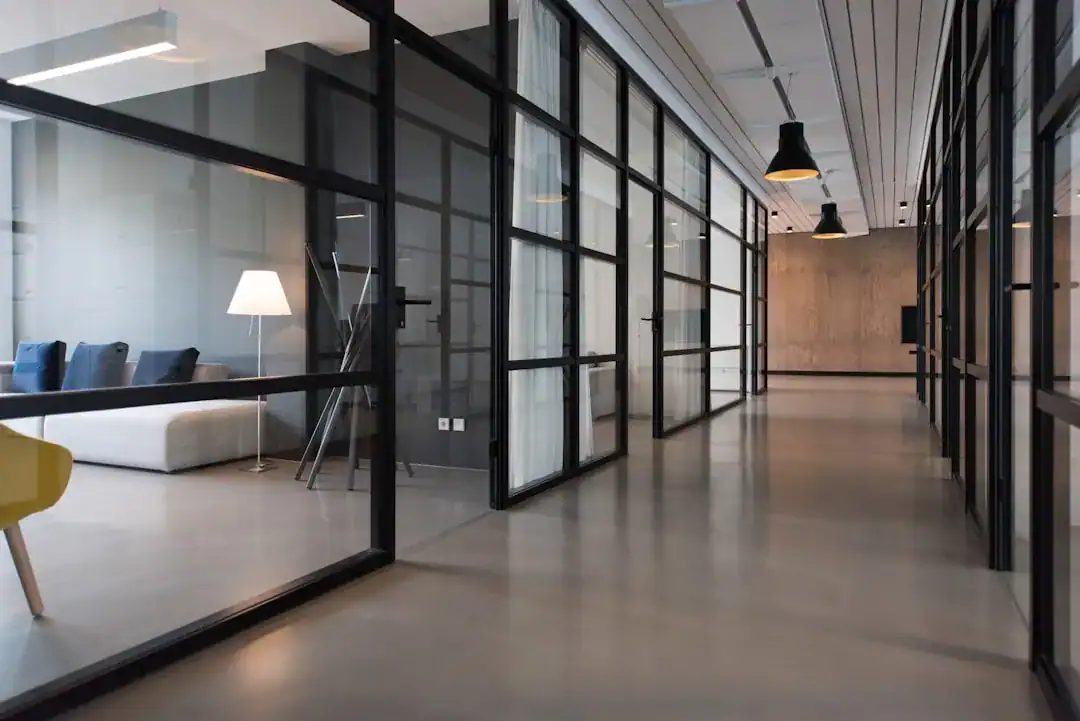 Glass-Walled Office Corridor with Industrial Vibe Modern office hallway with glass partitions and industrial lighting