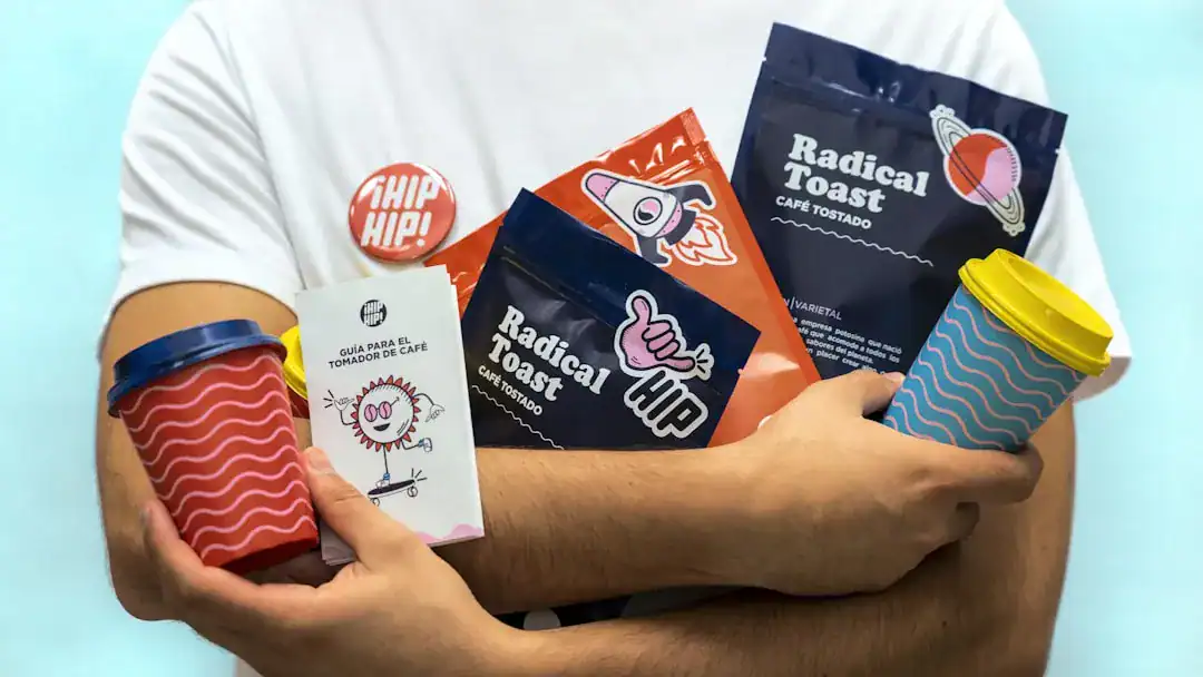 Bold coffee packaging lineup featuring Radical Toast Person holding assorted coffee bags and colorful takeaway cups with bold logos