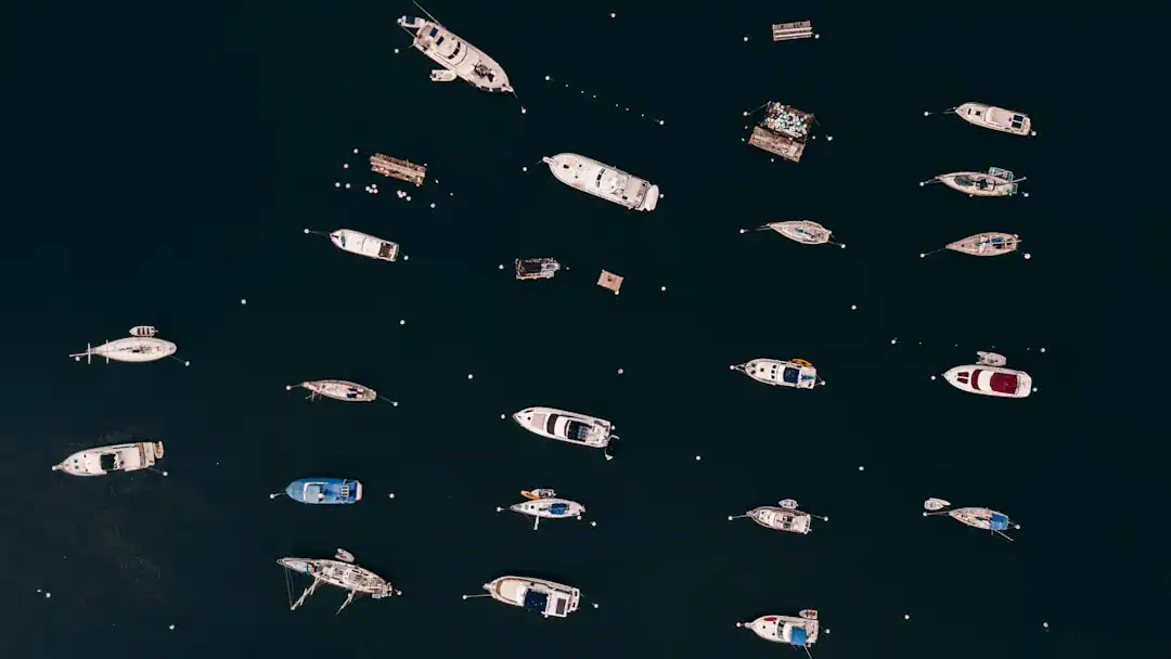 Aerial View: Fleet of Boats on Dark Blue Sea Aerial view of many boats on dark blue water