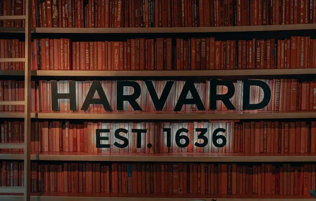 Harvard EST. 1636 sign on red book shelves in a library.