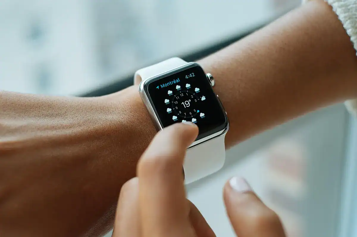 Close-up of a hand tapping a white smartwatch on the wrist
