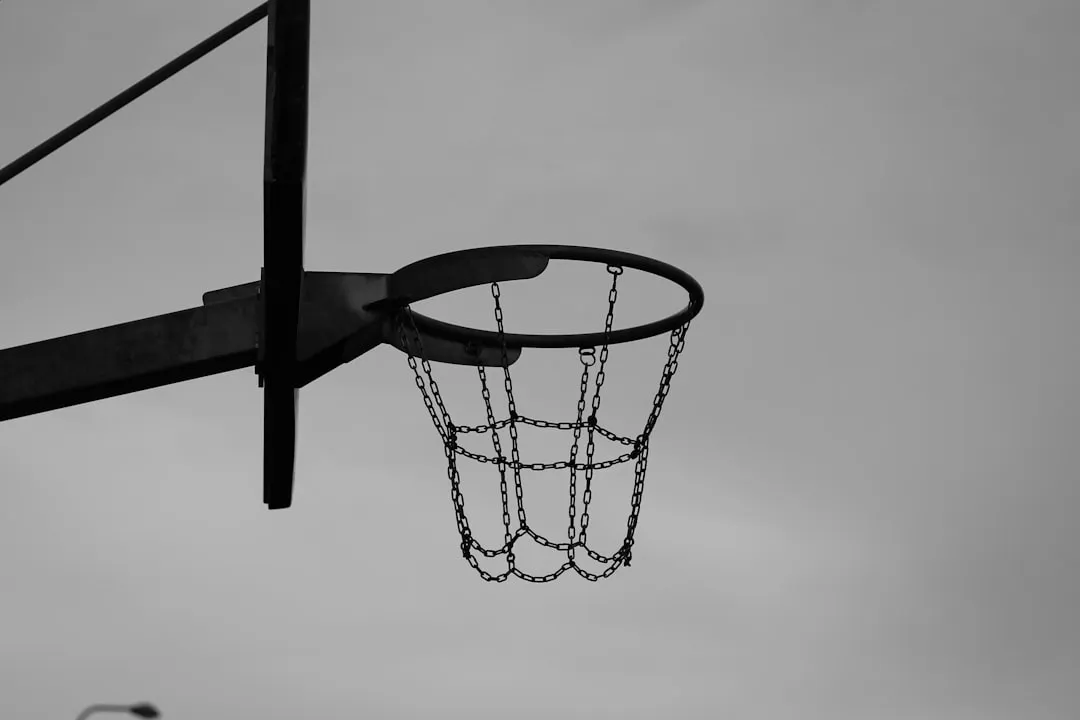 Black-and-white basketball hoop with chain net against a cloudy sky